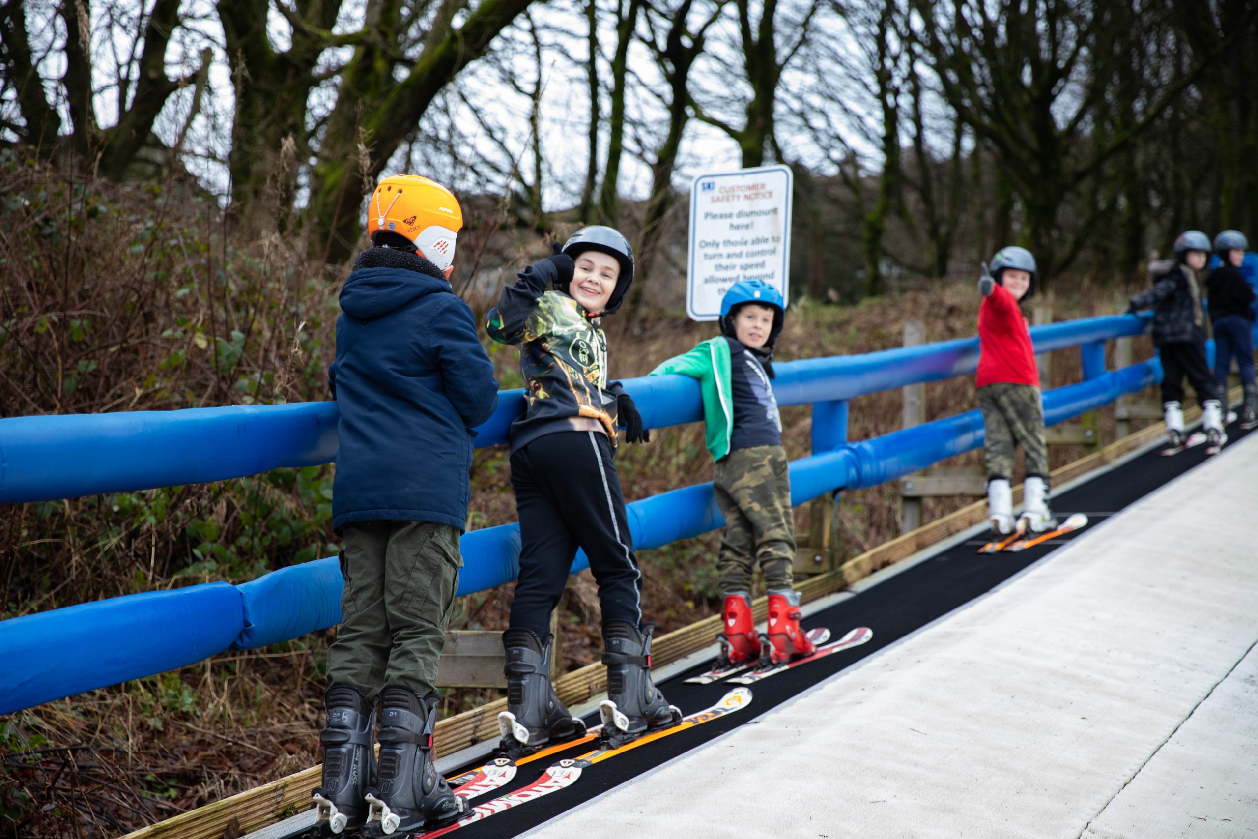 After school ski club for aged 5 years up. Group of boys on ski lift going to top of slope